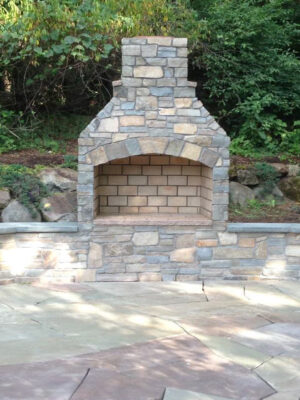 Outdoor fireplace built into a patio with stone benches 