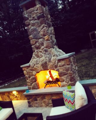 stone outdoor fireplace with a fire burning