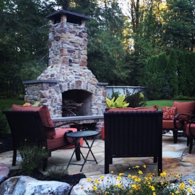 patio with seating around an outdoor fireplace with a chimney cap